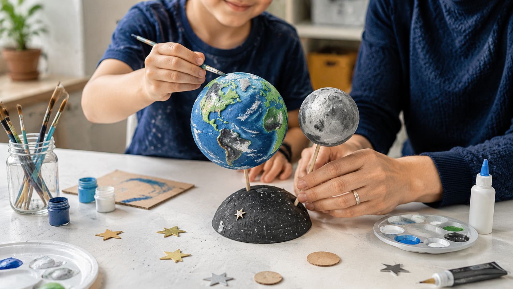 A child and an adult working together on a DIY school project featuring Earth and Moon models.