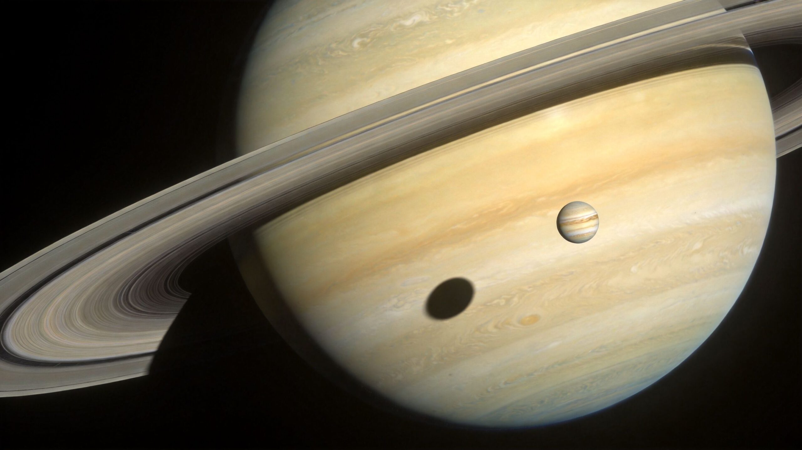 A digital composite image of Saturn featuring its iconic rings and Jupiter floating in front.