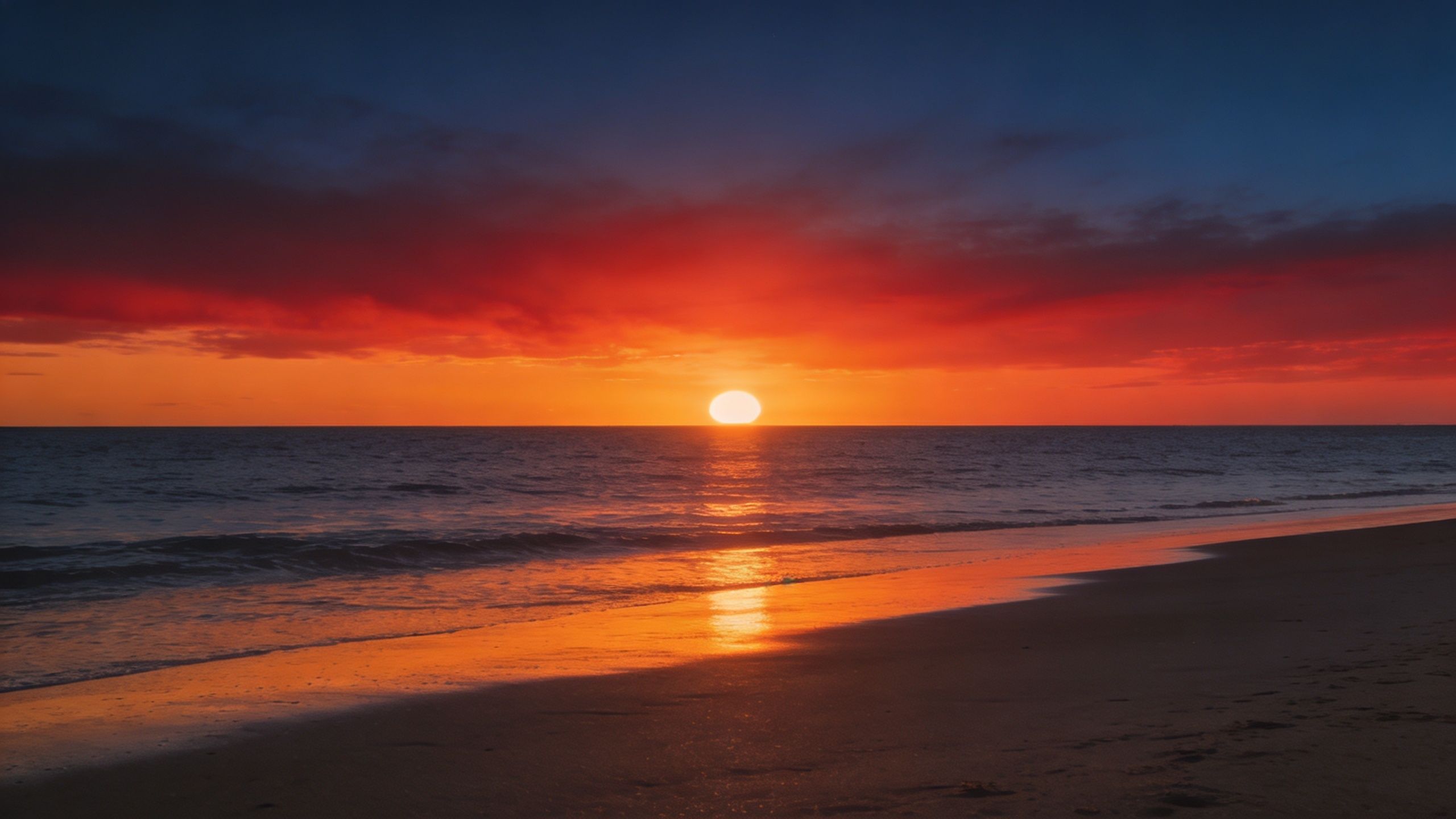 A stunning sunset over the ocean with vibrant red and orange clouds reflecting on the wet sand.
